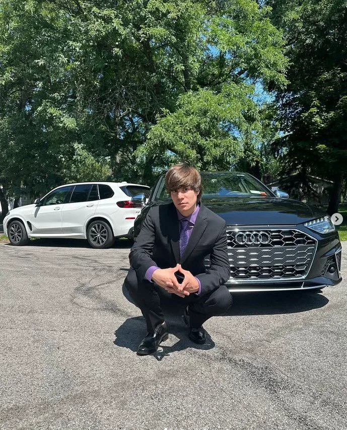 Max in a suit in front of an Audi