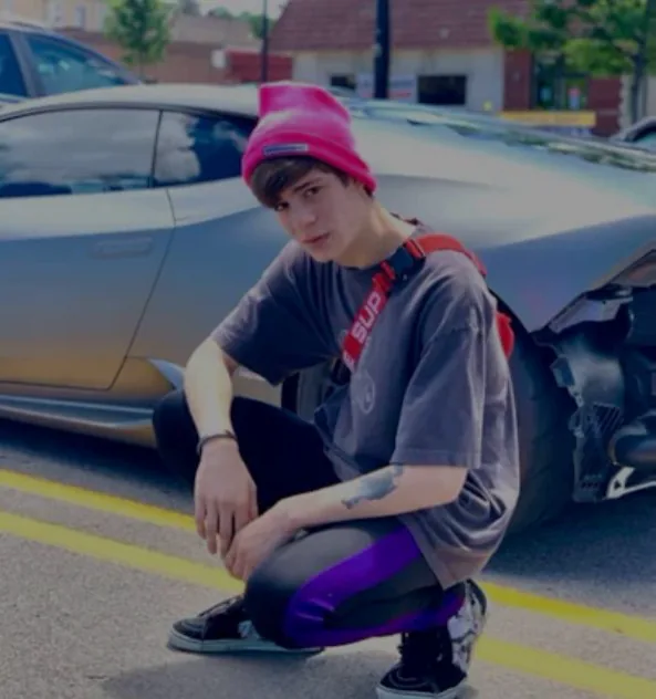 Young Max crouching by a car